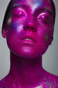 The fashionable photo of the young woman with creative cosmetics on a beautiful face. Space, spangles and multi-colored pigments in cosmetology. A make-up for Halloween, a carnival