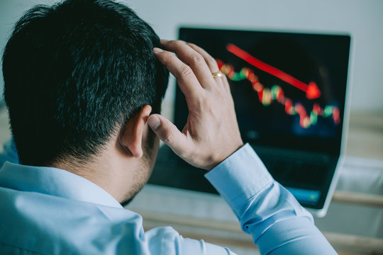 Stress Business man look at to the laptop show financial market chart graphic going down.  Stock market concept.