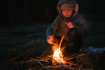 Seven-year-old boy light a fire in the woods.