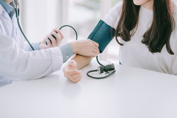 Doctor using sphygmomanometer with stethoscope checking blood pressure to a patient in the hospital. - obrazy, fototapety, plakaty