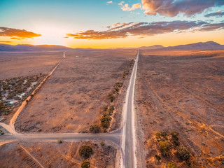 Rural highway leading into Ikara-Flinders Ranges national park at sunset - aerial view