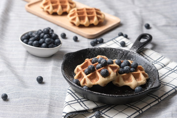 Belgium waffle with blueberry topping in the pan on the tablecloth