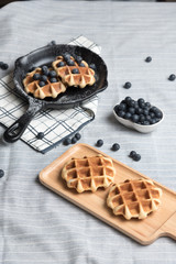 Belgium waffle with blueberry topping in the pan on the tablecloth