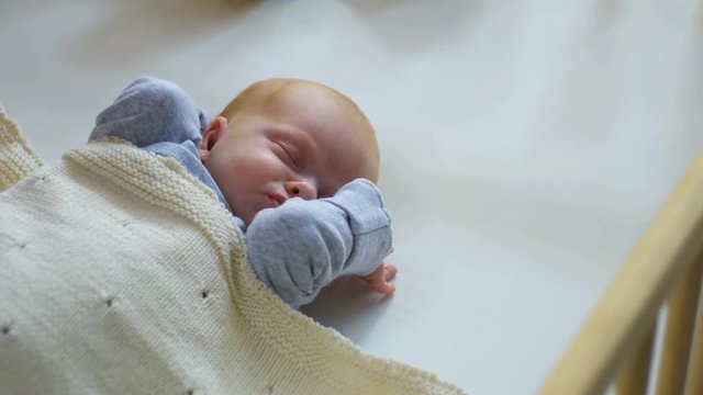 Mother cover her baby with a blanket in a white bed, warm concept and healthcare