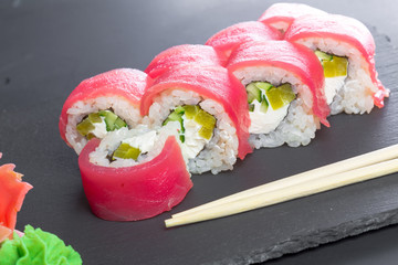 Japanese restaurant, sushi roll on black slate plate.