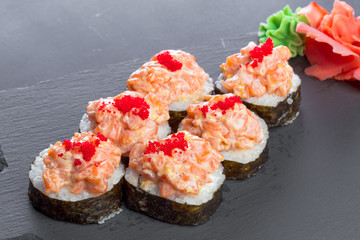 Japanese restaurant, sushi roll on black slate plate.