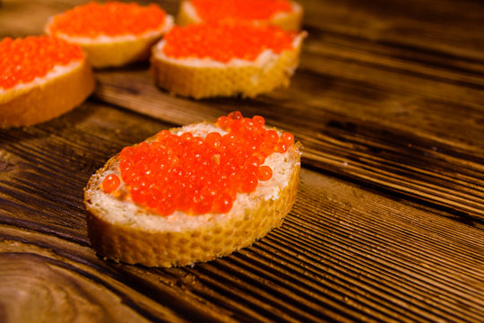 Sandwiches with red caviar on wooden table