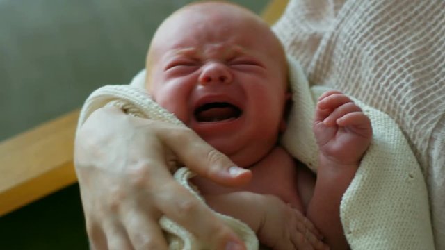Newborn baby cries on the mothers hands