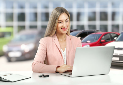 Woman working at table with laptop and car key isolated on white