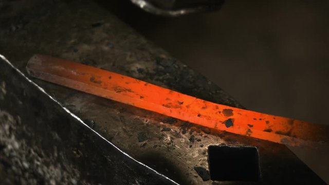 Blacksmith manually forging the molten metal on the anvil in slowmotion