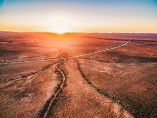 Orange sunset over dry land and rural highway passing through