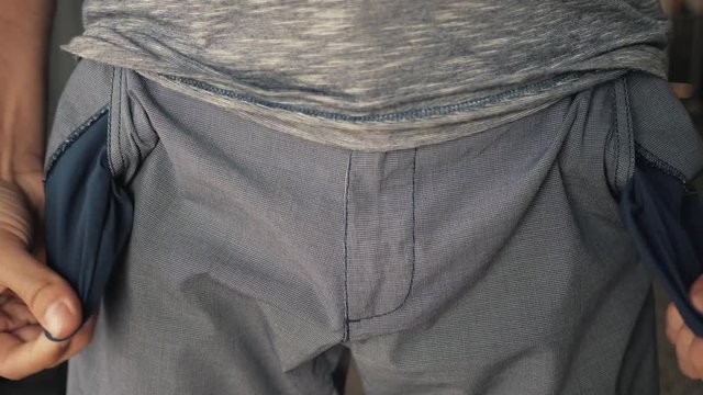 A business man showing his empty pockets on the background color. The concept of bankruptcy and ruin.