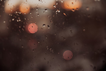 Drops of water during the rain in a city. Glass covered with rain. Blurred texture.