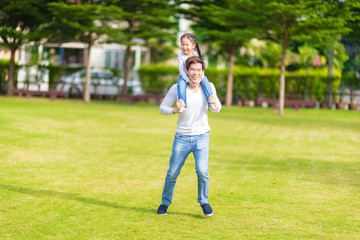 Cute Asian girl on neck dad big happy laughing and run around together. Happy man piggybacking adorable little kid is smiling.