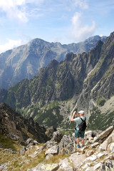 Fototapeta na wymiar In the summer, the tourist takes pictures of the mountain peaks of the High Tatras.
