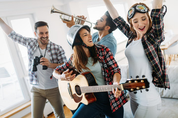 Cheerful friends having party together and playing instruments