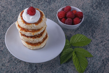 a pile of pancakes with cream and fresh berries on a wooden background closeup