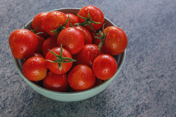 ripe red tomatoes in a ceramic bowl on a wooden table