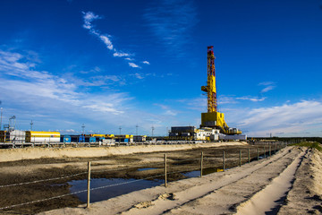 drilling rig on land with amber behind barbed wire