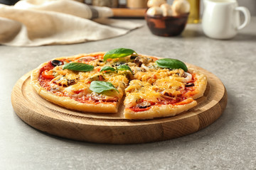 Wooden board with tasty pizza on table