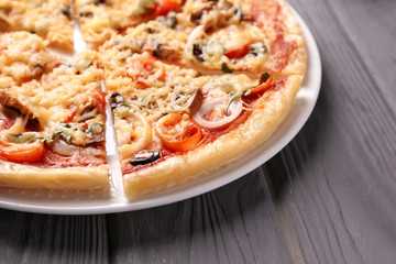 Plate with tasty sliced pizza on wooden table, closeup