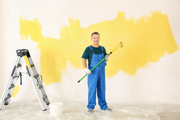 Male painter in uniform with roller brush indoors