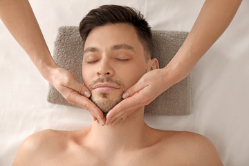 Fototapeta na wymiar Handsome man having facial massage in spa salon