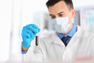 Scientist holding test tube with sample in laboratory