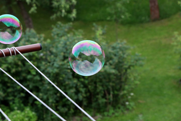 A colourful bubble flying in the air above garden and trying fly away. Bubble was created bubble...