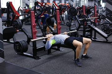 Fototapeta na wymiar Athletic man training with barbell in modern gym