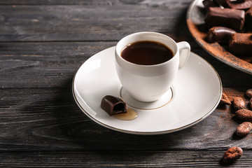 Cup of coffee with chocolate candy on wooden table