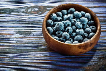 Huckleberries in round wooden bowl on wood board