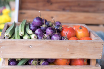 Purple eggplant tomato and okra in a wooden crate