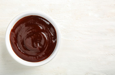Bowl with barbecue sauce on white table