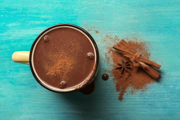 Mug of tasty hot chocolate on wooden background, top view