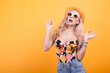 Cool beautiful young woman wearing eyewear glasses, in studio with hat over yellow background