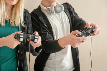 Young people with gamepads on color background