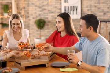 Young people eating pizza at table