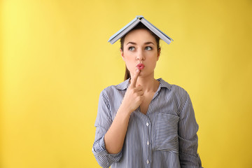 Funny young woman with book on color background