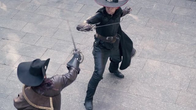 The top view of a man in a black cloak is knocked out one of the swords