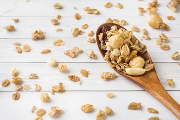 Fototapeta premium Dry Breakfast of oat flakes, granules and nuts. Muesli on a light table in a wooden spoon.