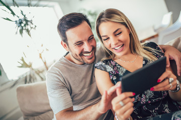 Attractive happy married couple using digital tablet at home.