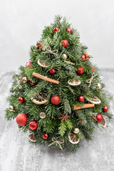 Christmas or New Year greeting card. Decorative fir. Pine branches, red balls, cinnamon sticks and orange slices on old wooden background. Vintage style, selective focus.