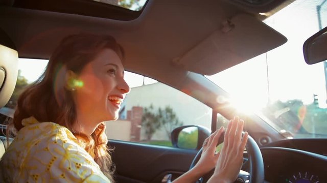Medium shot of young beautiful woman driving and enjoying her music. she taps her thumbs on the steering wheel and moves to the beat of the song.