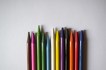 Multicolored pencils on white background. A palette of pencils on a table, close up.