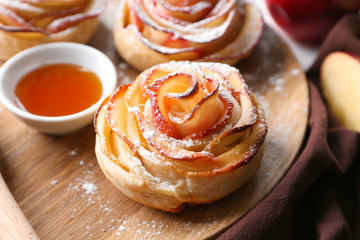 Obraz na płótnie Canvas Tasty rose shaped apple pastry and honey on wooden tray, closeup