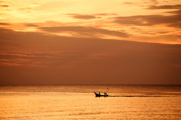 Fototapeta premium Fishermen out fishing at sunrise in the sea, amidst the clouds and the sky is beautiful