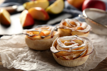 Tasty apple roses from puff pastry on table