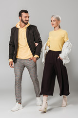 smiling couple of models in stylish autumn outfits on grey background