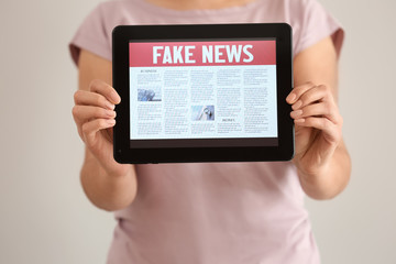 Woman holding tablet computer with news on screen